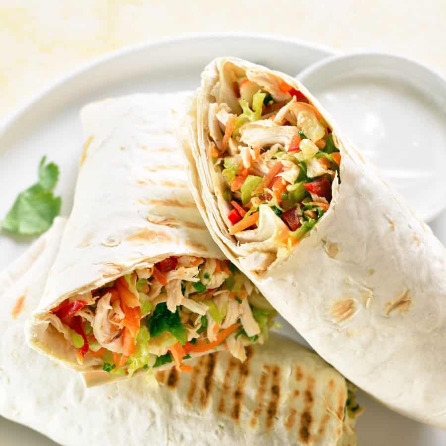 Lunch: Turkey and Avocado wrap with veggies on a white plate.