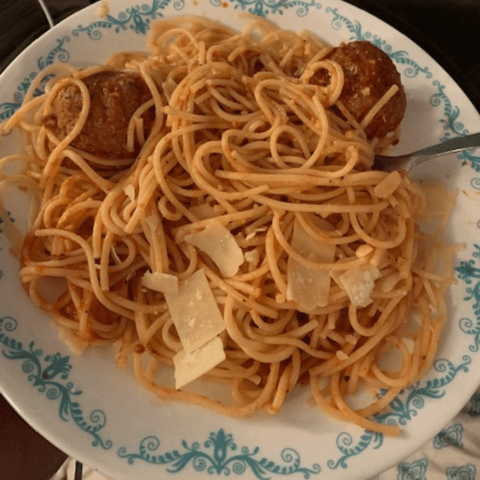 Cooked Grandma's meatball dinner with parm on a ehite dinner plate.