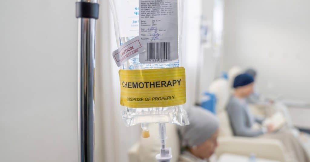 IV pole with a chemo bag and a Cancer patient in the background