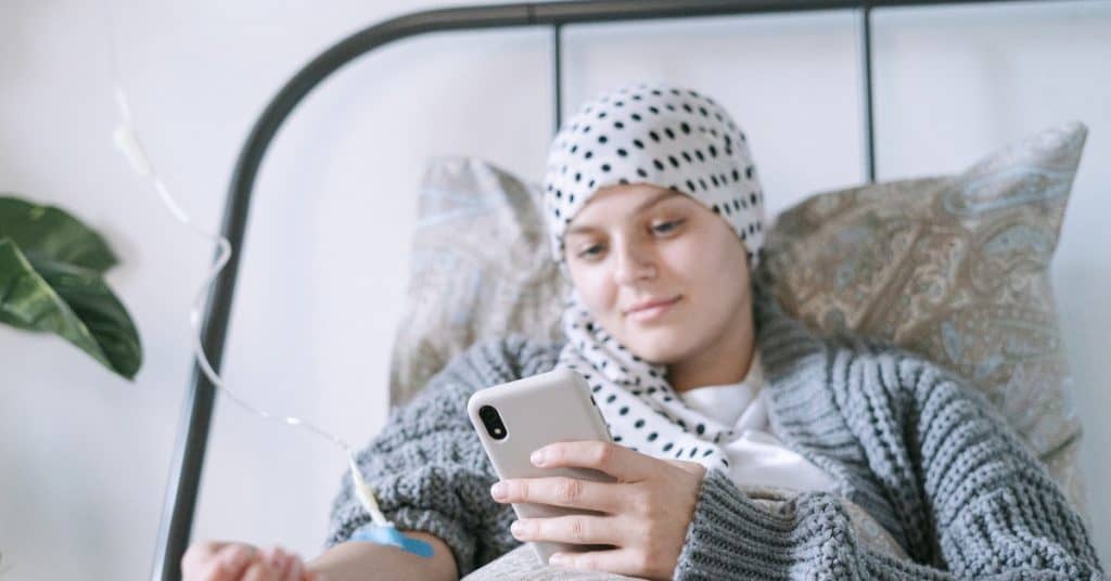 Cancer patient using her phone during treatment.