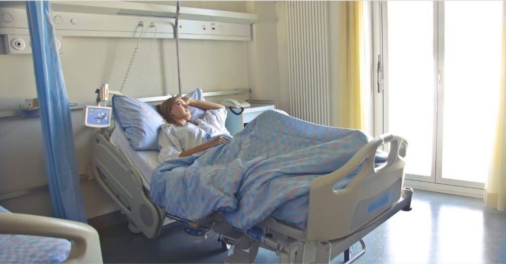Stressed woman lying in a hospital bed receiving medical care.
