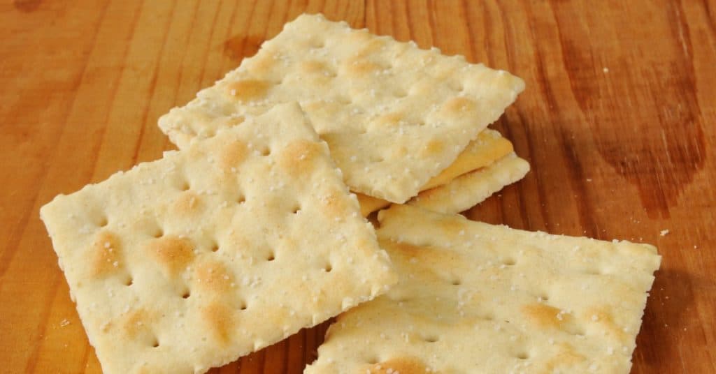 Saltine crackers on a wooden cutting board,